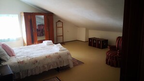 A bedroom with a bed, a wardrobe, a chair, and a small cabinet.