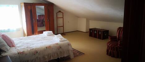 Un dormitorio con cama, armario, silla y un mueble pequeño.
