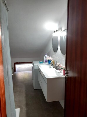 A modern bathroom with a large mirror, a white sink, and a shower area.