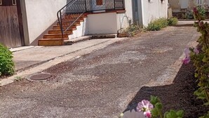 Un edificio a due piani con una scala, un piccolo balcone e un ingresso chiuso da cancello.