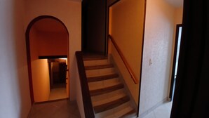 Una scala con gradini in legno e una ringhiera, che porta a un pianerottolo con una porta.