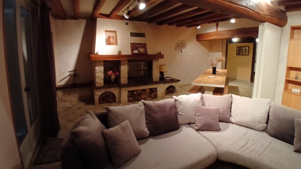 Un accogliente soggiorno con un divano componibile, camino e travi in legno.