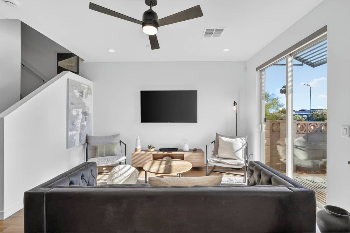 A modern living room with a sofa, coffee table, and a flat-screen TV mounted on the wall.