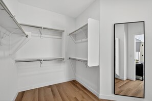 Een kamer met witte wanden, een houten vloer en een grote spiegel die het interieur weerspiegelt.