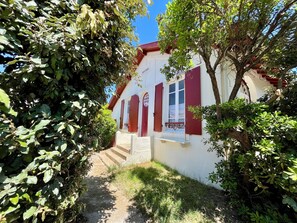 En bygning med en hvid facade, røde markiser og et lille vindue med et mønstret gardin.