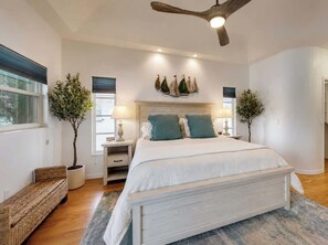 Ein Schlafzimmer mit Bett, Nachttischen, Deckenventilator und Wandbildern.