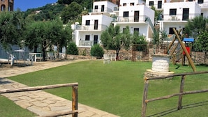 Un patio con césped cuidado, mobiliario exterior y un muro de piedra.