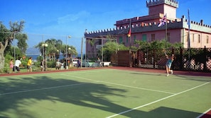 A tennis court with a castle-like building in the background.