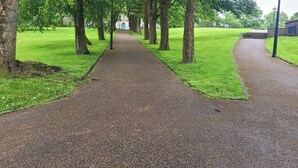 A paved pathway flanked by trees in a park setting. - Palace Court in the Heart of Buxton (Buxton)