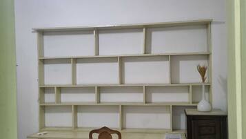 Um quarto com escrivaninha, cadeira e estante.