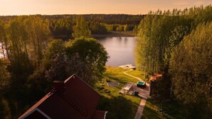 Talo, jossa on punainen katto, lampi ja metsäinen alue.
