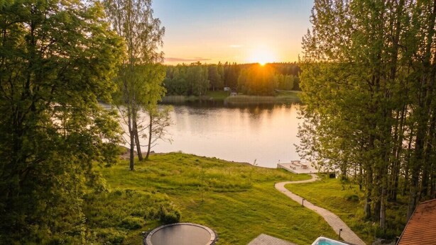 Järvenrantaterassi, jossa on poreallas, puinen penkki ja pyöreä nuotiopaikka.