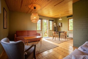 Una habitación acogedora con techo de madera, un sofá, una mesa de comedor con sillas y una lámpara colgante.