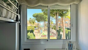 Una habitación con cama, ventana con vista a un parque, una mesita y un cuadro colgado en la pared.