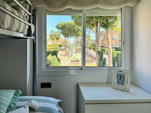 Ein Zimmer mit einem Bett, einem Fenster mit Parkblick, einem kleinen Tisch und einem an der Wand hängenden Bilderrahmen.