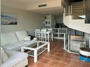 Ein modernes Wohnzimmer mit Sofa, Couchtisch und Essbereich.