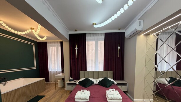 Ein modernes Schlafzimmer mit einem großen Bett, Nachttischen, einem Schminktisch und einem begehbaren Kleiderschrank.