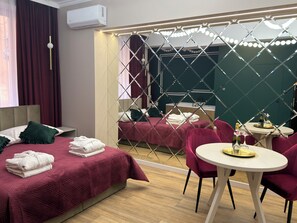 Ein Hotelzimmer mit Bett, Spiegel, Tisch mit Stühlen und einer Minibar.
