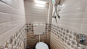 Een badkamer met toilet, boiler en betegeling met patroon.