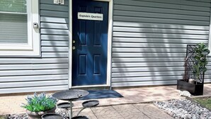 A house with a dark blue door labeled 'Captain's Quarters,' a small outdoor table, a potted plant, and a decorative metal piece. - Captain’s Quarters- charming studio apartment in the countryside (Berlin Center)