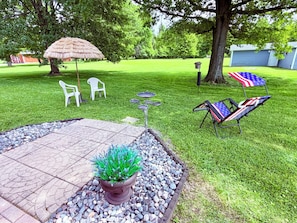 A patio area with a stone table, chairs, a potted plant, and an American flag chair.