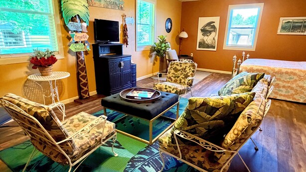 A living room with a television, two armchairs, a sofa, a small table, and a decorative wall. - Captain’s Quarters- charming studio apartment in the countryside (Berlin Center)