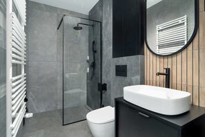 Ein modernes Badezimmer mit einer Duschkabine aus Glas, einer weißen Toilette und einem schwarzen Waschtisch mit einer weißen Spüle.