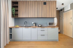 Eine moderne Küche mit einer Holzauslage, einem grauen Unterschrank, einer Mikrowelle, einem Wasserkocher und einer Spüle.