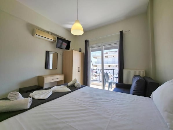A hotel room with a bed, a TV, a wardrobe, a mirror, and a balcony with a table and chairs. - HOTEL GALINI (Katerini)