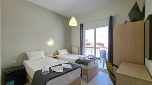 A hotel room with two beds, a desk, a chair, a TV, and a balcony with a view. - HOTEL GALINI  (Katerini)