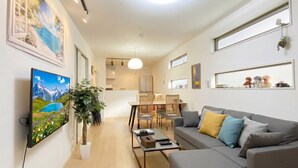 Una sala de estar moderna con sofá, mesa de centro y comedor con sillas y una mesa.