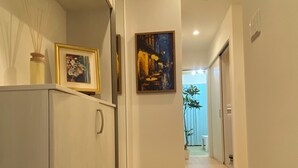 Un pasillo con un perchero para zapatos, un cuadro enmarcado y un cuadro en la pared.