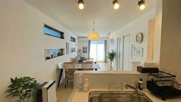 Una cocina moderna con comedor, horno empotrado, pileta con escurreplatos y una planta en maceta.