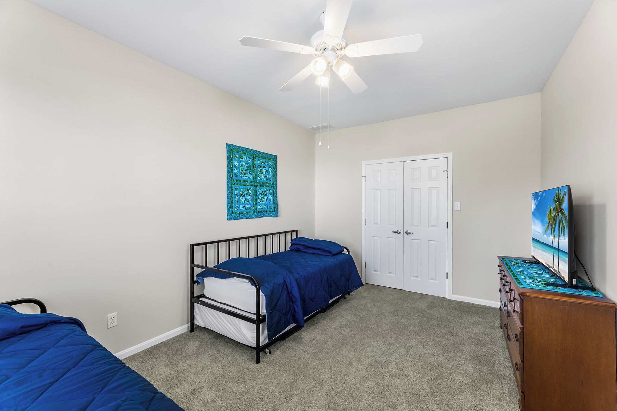 Une chambre à coucher avec un lit, un ventilateur de plafond, une commode et une porte.