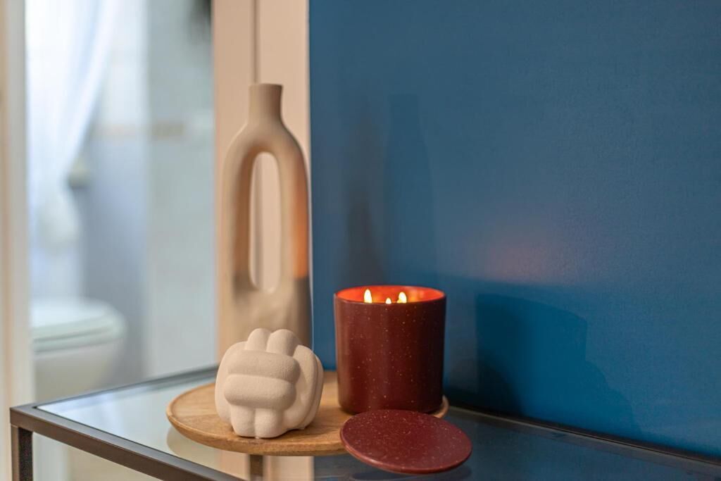 A glass table with a candle, a white decorative object, and a red candle holder.