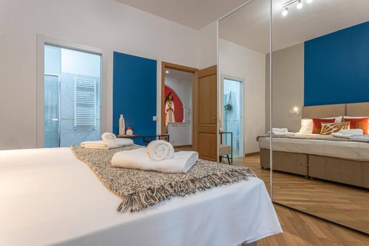 Un dormitorio con cama, espejo, armario y puerta que da a un baño.