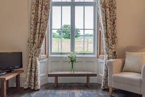 A room with a large window, a bench, a television, and a sofa. - Ficerdy -  a self catering cottage that sleeps 6 guests  in 3 bedrooms (Llandwrog)