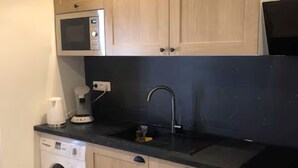 A compact kitchen with a washing machine, microwave, and a sink with a faucet. - Maison Vallée: Swimming Pool / Groupama Stadium / Euroexpo / LDLC ARENA / Access to Downtown (Décines-Charpieu)