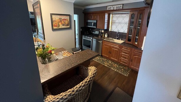A kitchen with wooden cabinets, a granite countertop, a stove, and a sign that says 'let's eat'. - Lakefront home located 10 minutes from the Hardrock Stadium for the World Cup (Miami)