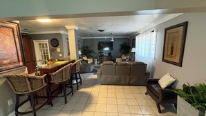A spacious living area with a dining table, chairs, a sofa, and a television. - Lakefront home located 10 minutes from the Hardrock Stadium for the World Cup (Miami)