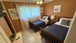 A hotel room with two beds, a ceiling fan, a window with sheer curtains, and a small table with a lamp. - Lakefront home located 10 minutes from the Hardrock Stadium for the World Cup (Miami)