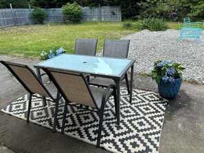 Eine Terrasse im Freien mit einem Tisch aus Glas und vier Stühlen, umgeben von einem gemusterten Teppich.