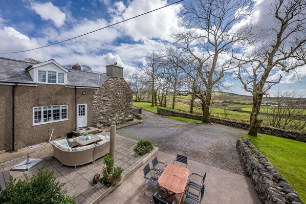 A stone house with a patio, outdoor seating, and a view of the countryside.