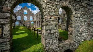 An ancient stone structure with arched passageways and a grassy foreground. - Braich-Y-Big -  a self catering cottage that sleeps 5 guests  in 3 bedrooms (Garndolbenmaen)