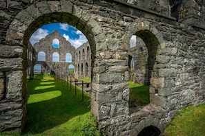 An ancient stone structure with arched passageways and a grassy foreground.