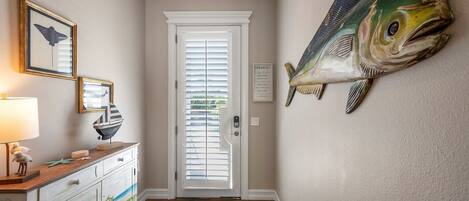 A hallway with a wooden dresser, a framed picture, a lamp, and a large fish mural on the wall.