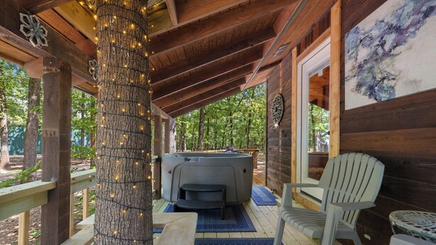 Un espacio exterior cubierto con un jacuzzi, una terraza de madera y una silla.