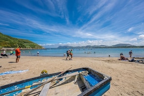 Ein Strand mit einem Boot, Menschen und blauem Himmel.