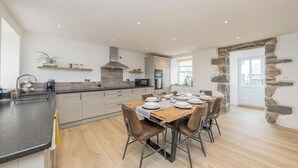 A modern kitchen with a dining area, featuring a stone archway, built-in appliances, and a clean, minimalist design.