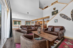 A spacious living room with leather sofas, a wooden coffee table, and a kitchen in the background. - Fairway Getaway Near Mille Lacs 3 Bedroom Home (Onamia)